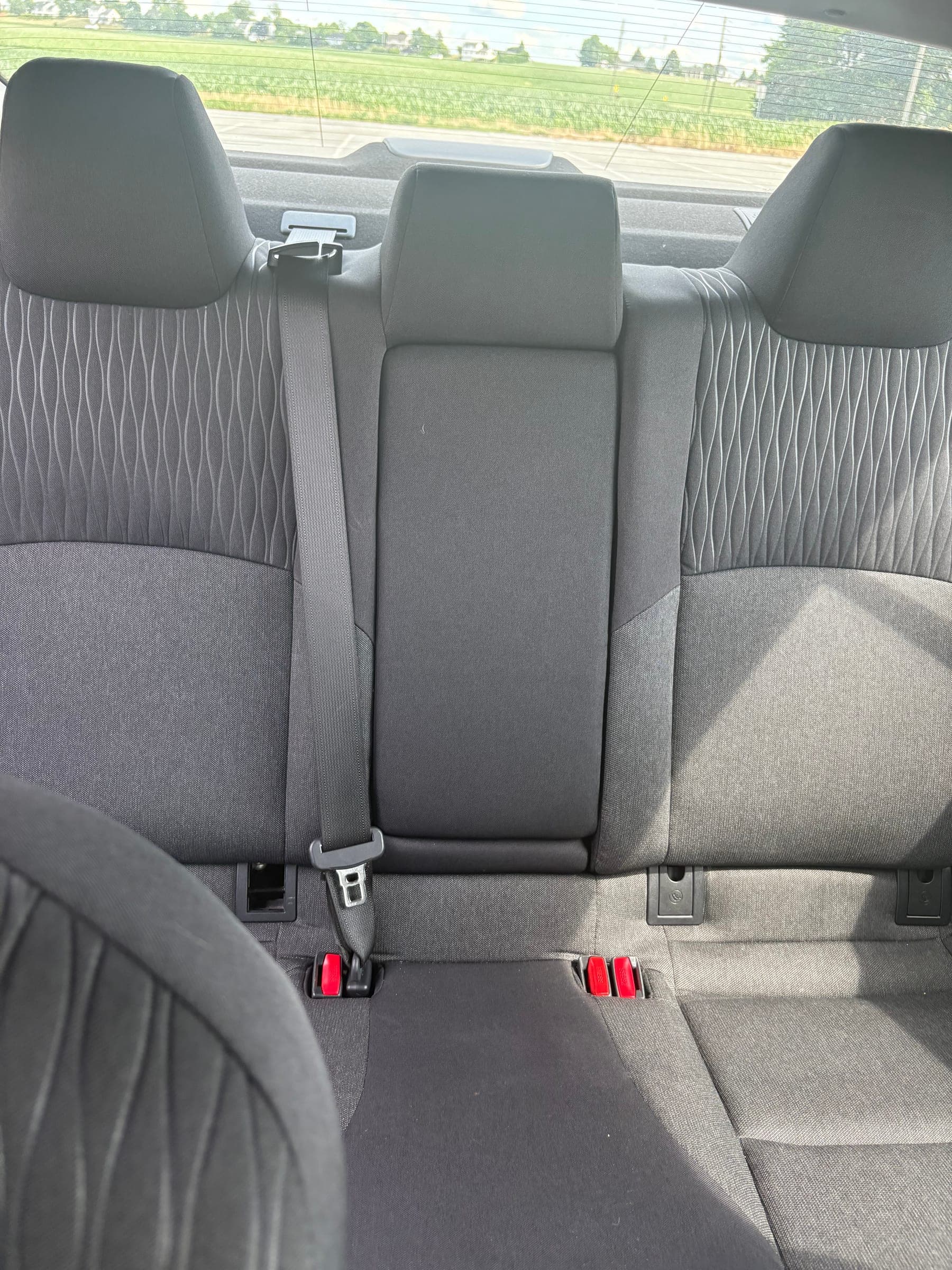 Freshly cleaned rear bench seats with the center armrest down, showing the full width of the quilted fabric