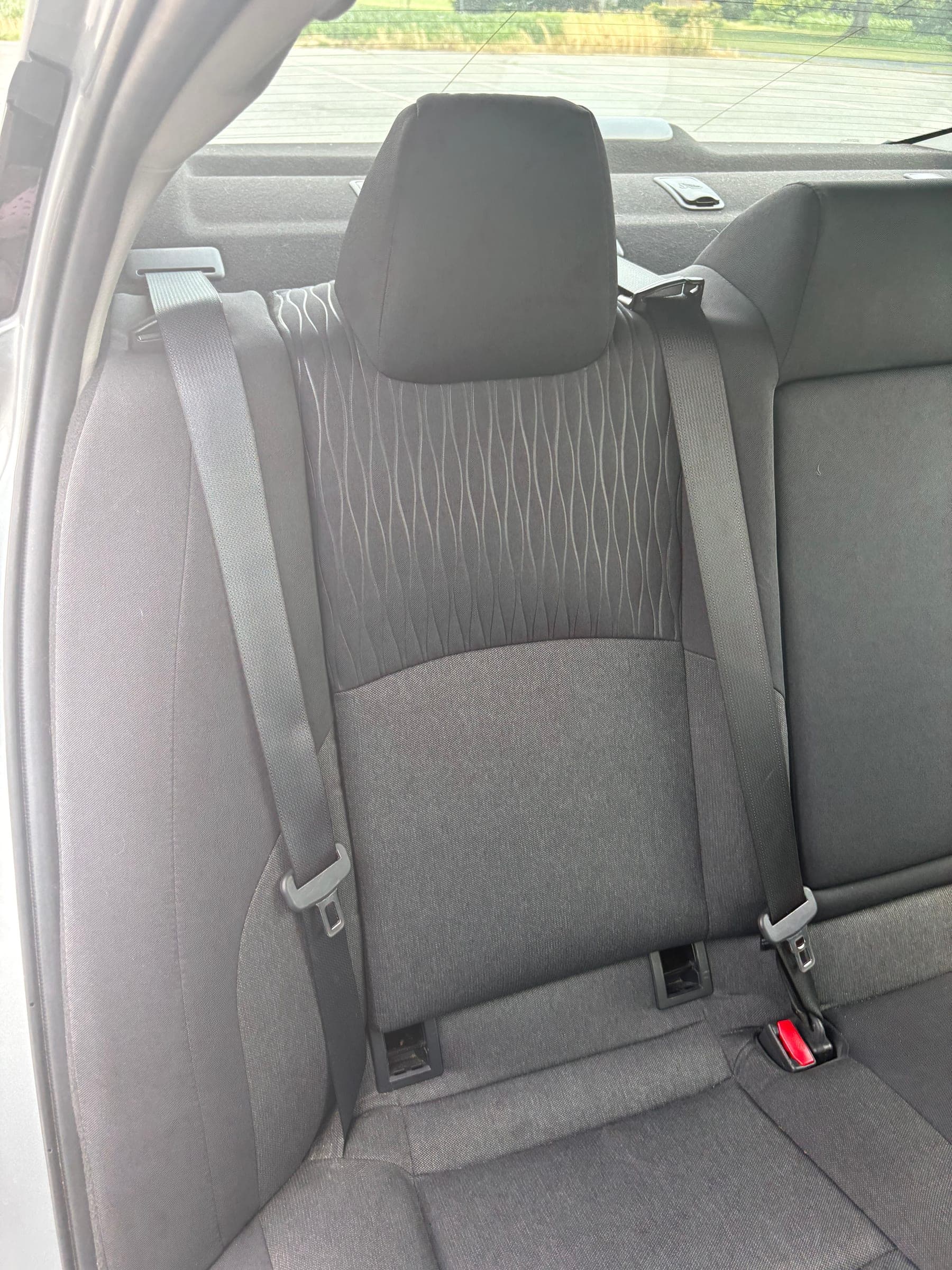 Close detail of a rear seat cushion with diamond-quilted fabric and clean seatbelt hardware